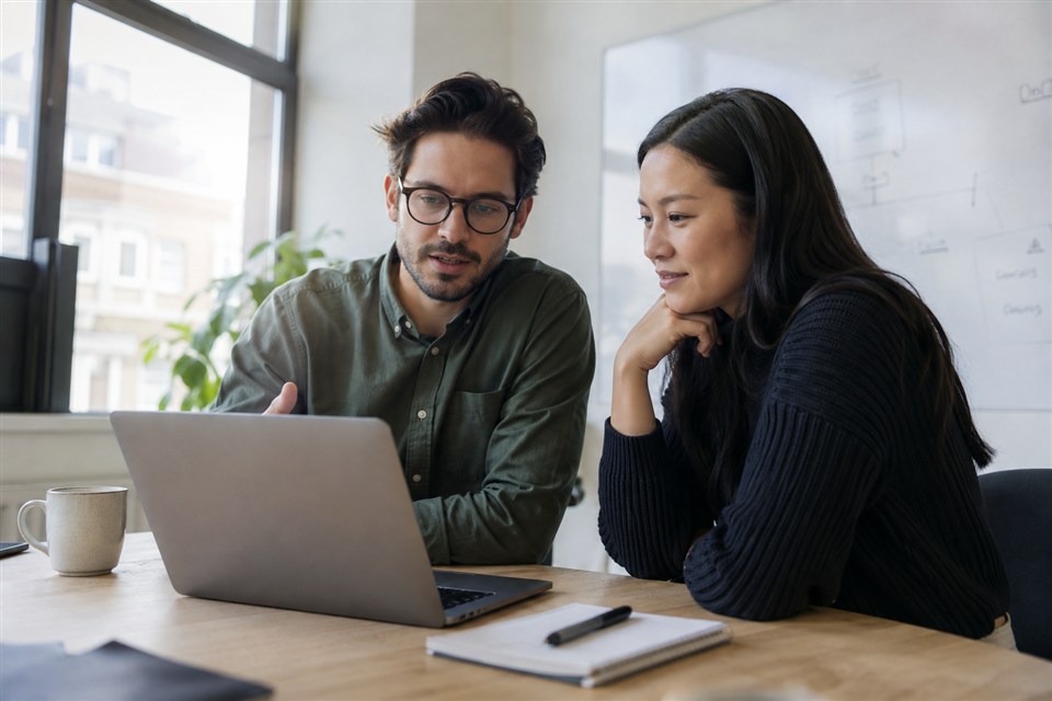 Colleagues reviewing a laptop during a project walkthrough